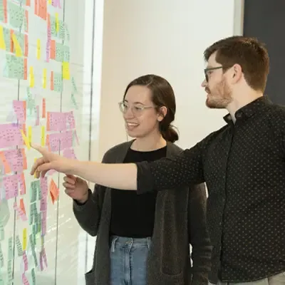 Students reviewing project wall of sticky notes.