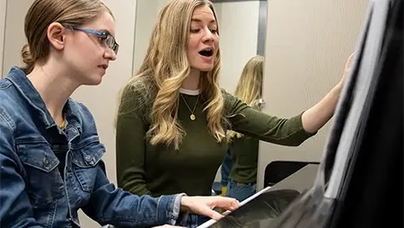 Female students playing piano and singing.