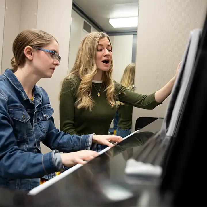 Female students playing piano and singing.